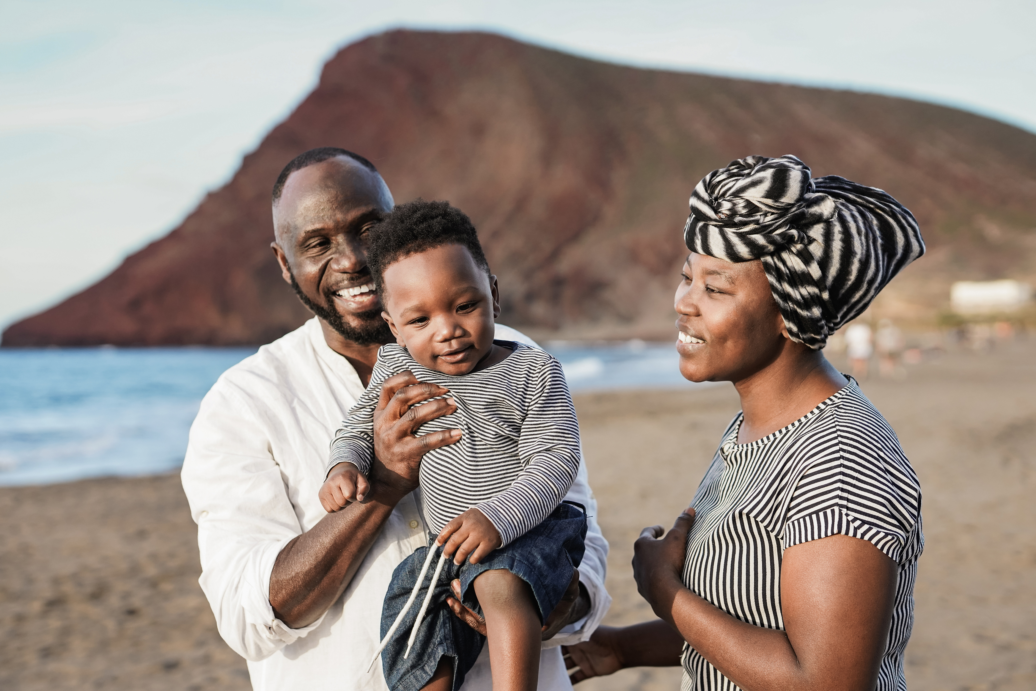 Happy african family enjoy vacation on the beach with little son - Parents and toddler outdoor