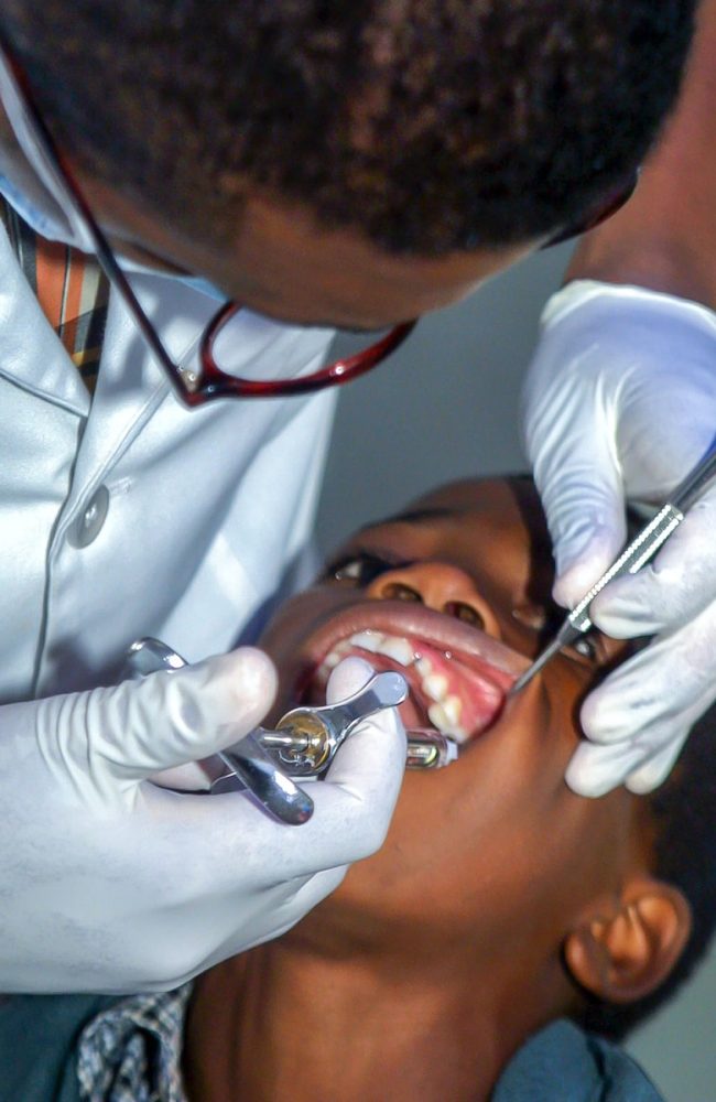 dentist holding syringe into boy's mouth